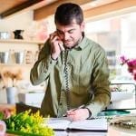 Caucasian man answering the phone in a retail flower shop