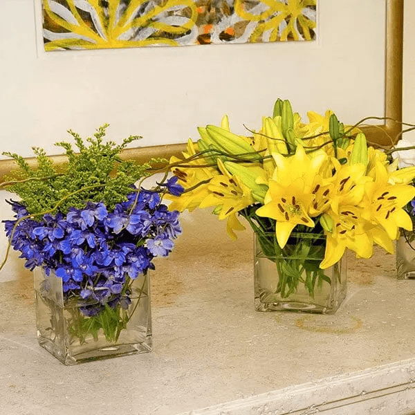 Middle aged asian female smelling a flower arrangement, smiling.